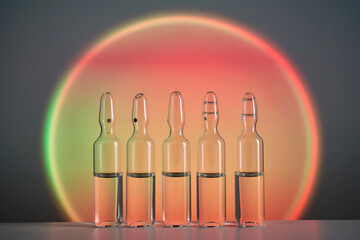 Ampoules for injection against the background of a bright orange circle.