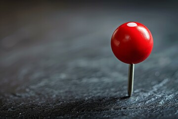 A red pin on a black surface with a black background
