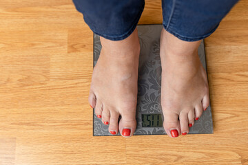 A picture of female feet standing on a floor scales
