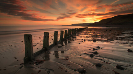 A beach with a wooden fence and a sunset in the background