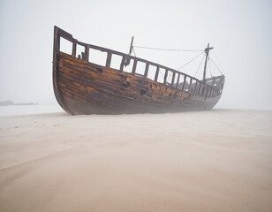 old abandoned shipwreck at the shore on a misty day