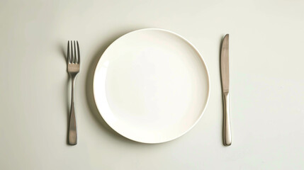 A silver fork and knife are on a white plate. The plate is empty, and the silverware is clean. Concept of simplicity and minimalism, with the focus on the basic elements of a meal