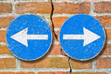 Arrow signs against a brick wall indicating to go left and right - Choice concept, dividing,...