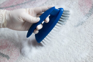 Blue brush on the floor with hand in rubber glove. Cleaning.