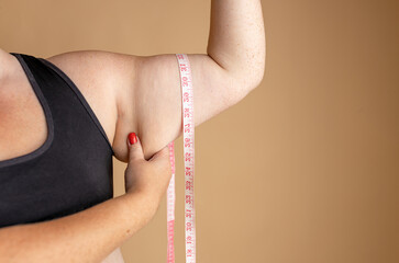 Arms of overweight woman on beige background. Diet concept