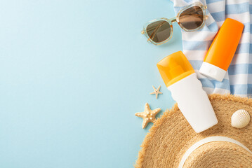 Top-view shot featuring SPF skincare bottles, sunhat, sunglasses, and beach essentials on a pastel blue backdrop. Protect your skin from UV rays while enjoying the sun. Ideal for skincare promotions