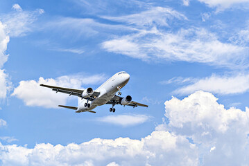 Passenger plane landing at the airport, under a blue sky with white clouds