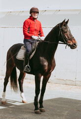 Amateur rider enjoying horseback riding in red outfit.