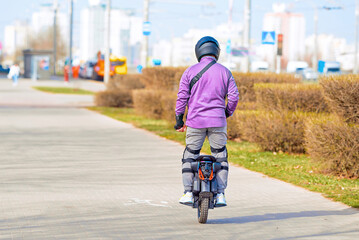 Man in safety gear riding EUC electric wheel on sidewalk. Man commuting on electric monowheel with protective gear, safety while riding. One wheel electric bicycle for better mobility in the city. © Tricky Shark