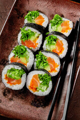 Futomaki rolls with salmon, tobiko and greens on rustic plate