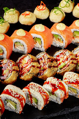 Specialty sushi rolls arranged on black slate board