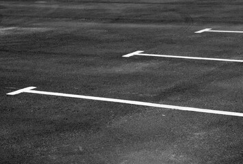 White road marking on asphalt of parking lot.