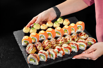 Female hands holding slate board with sushi variety