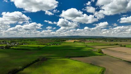 Drone footage view of the meadows in Ireland with beautiful blue sky and clouds