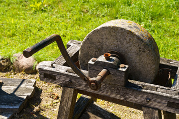 Vintage Grinding Wheel With Hammer in Bright Daylight on a Wooden Stand