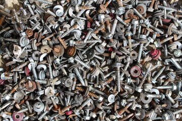 Old rusty screws and screws lie in a heap. Texture.