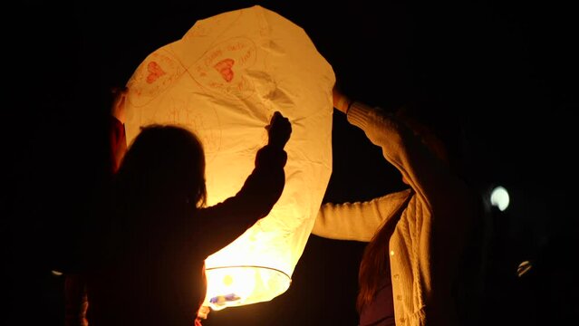 Silhouette of people holding large Chinese lantern