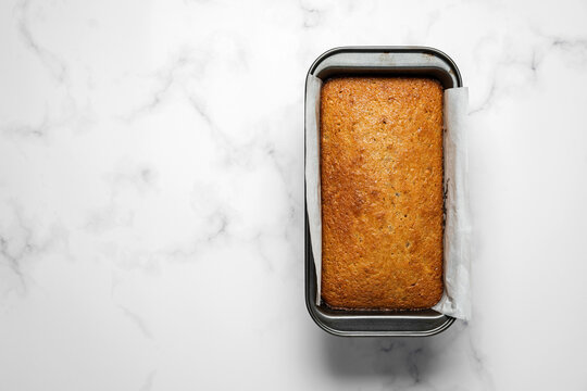 Banana bread loaf in a baking tin on marble background