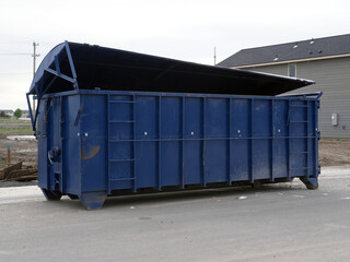 Large blue construction dumpster in front of new duplex homes under construction.