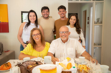 família em casa sentada a mesa pra tomar café da manhã, reunião de família, família feliz comendo. mesa de café da manha com frutas e pão.