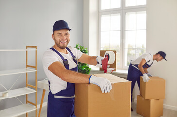 Moving company workers pack stuff for transportation to new house. Portrait happy smiling man in...
