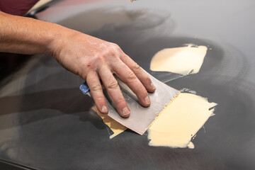 Detailed View of Mechanic Applying Body Filler on Car