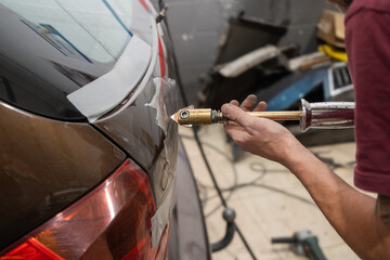 Mechanic Using Electric Dent Puller on Rear Car Door
