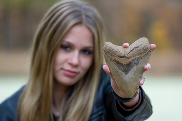 Young girl holding a large Megalodon shark tooth