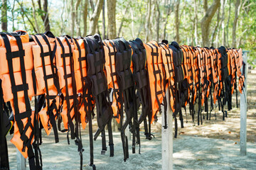 Row of orange life jackets or life vests for tourist hanging beside the beach waiting for use to...