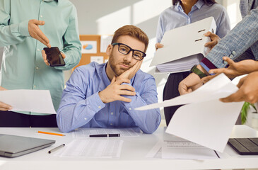 Stress, burnout and tired man sitting at the desk in office frustrated or overwhelmed by coworkers...