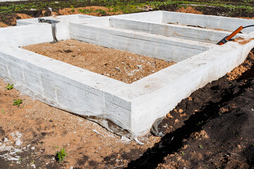 Construction of a new residential house under sunny skies, with the concrete foundation being laid on the construction site. The start of a solid base for the future development project