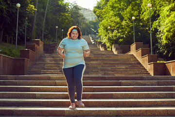 Overweight woman having jogging workout in park. Fat large plump girl in sportswear running down...