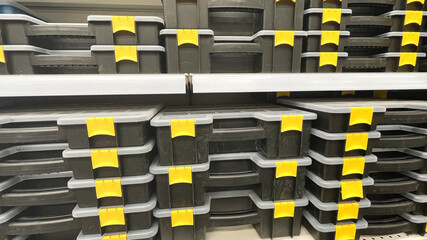 A shelf of plastic containers with yellow handles. The containers are stacked on top of each other....