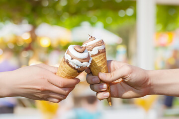 Two hands holding ice cream cone .