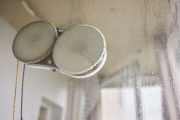 A robotic white Automotive tire is cleaning a glass window