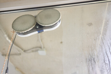 A robotic white Automotive tire is cleaning a glass window