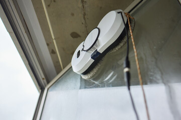 A robotic white Automotive tire is cleaning a glass window