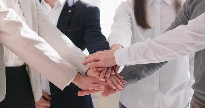 Close up of business people putting their arms together. Stack of hands of a group of company employees in office. The concept of unity, partnership and teamwork. 4k video. Slow motion video.