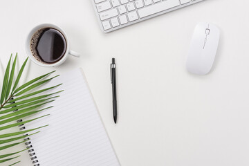 Workspace with computer keyboard, green leaf, and coffee cup