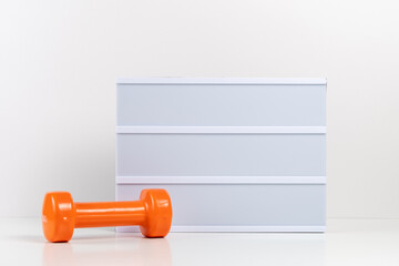 Fitness dumbbells with empty lightbox on white table. Mockup concept. - Powered by Adobe