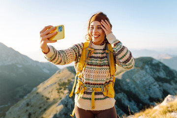 Young woman  taking selfie portrait on the top of mountain. Hiking, sport, travel and technology...