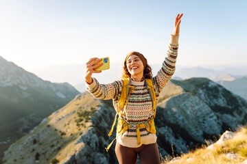 Young woman  taking selfie portrait on the top of mountain. Hiking, sport, travel and technology...