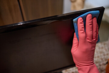 Close-up of hand cleaning television screen with cloth at home
