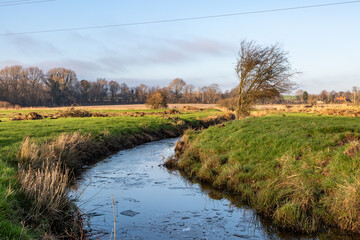 Looking along the River Ouse near Lewes, on a sunny winter's day, with ice on the water