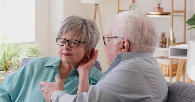 Senior people talking at home, woman having hearing loss problems, chatting with old man sitting on sofa, family couple, grandmother having trouble following conversation, feeling frustrated 
