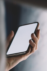 Close up view of hand holding modern smartphone with big blank screen for content template. Person using interactive internet kiosk and application on mobile phone. Copy space area for advertising