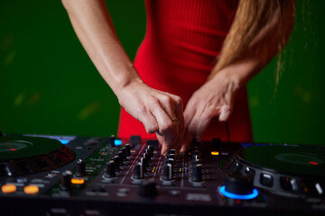 control DJ for mixing music with blurred people dancing at party in nightclub.