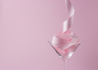 Martini glass with pink party ribbon. Minimal celebration concept.