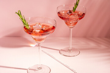 Refreshing cocktail with rosemary in a glass on a bright background. Summer party concept.