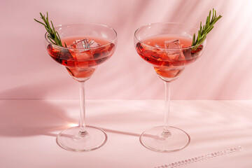 Refreshing cocktail with rosemary in a glass on a bright background. Summer party concept.